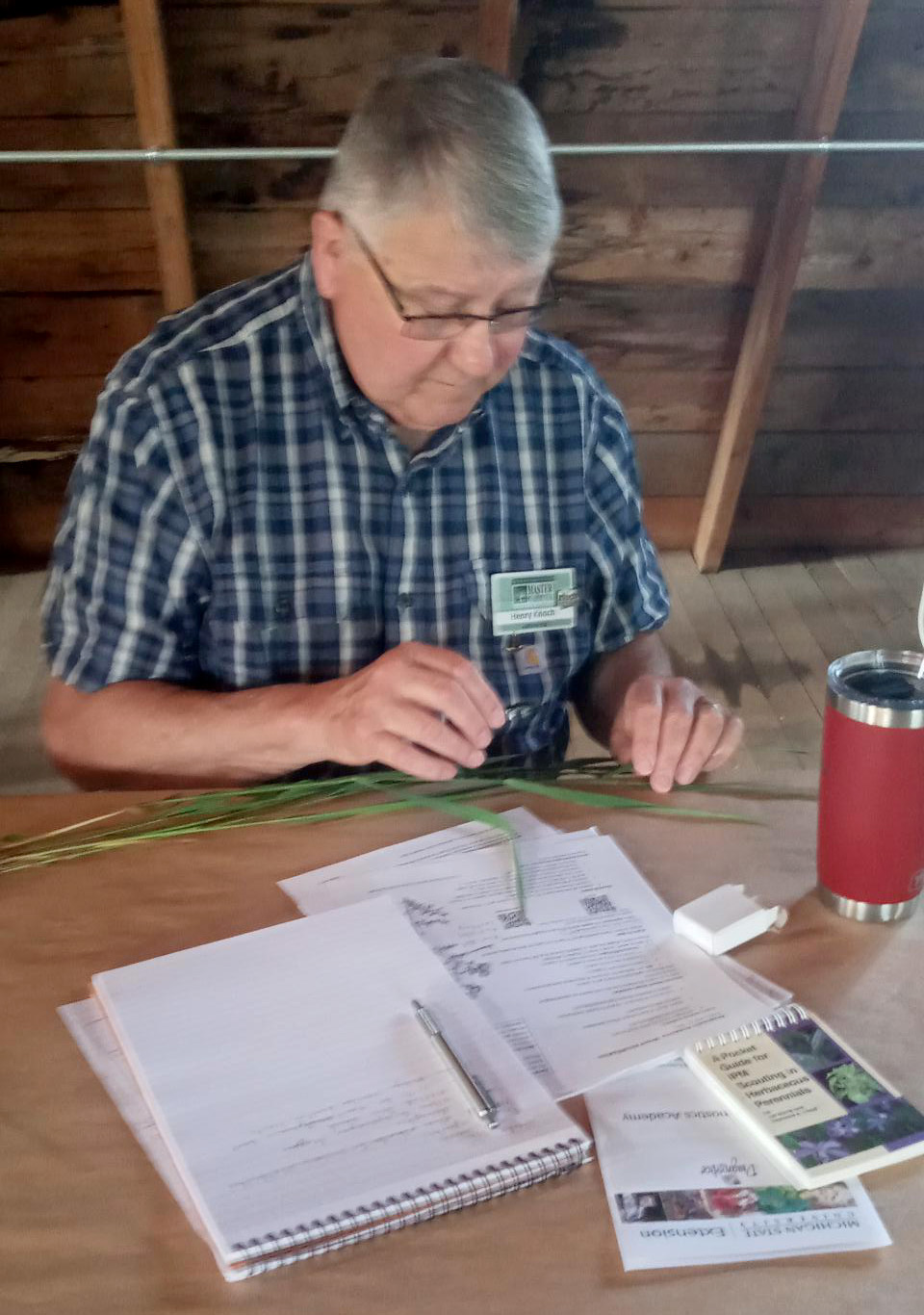 A man sitting at a table looking at grass samples.